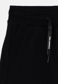 Zwarte jersey sweatpants met een koord in de taille, voorzien van zijzakken en een gestructureerde stof. Accents met een branded koordlabel.