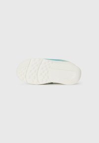 Semelle de chaussure avec un motif en caoutchouc texturé de couleur blanche, présentant une note turquoise sur le côté et un design lisse et plat.