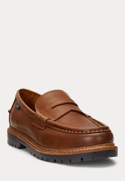 Ruskea nahkainen penny loafer -kenkä, jossa paksu ommeltu pohja ja kumipohja, sivussa pieni "Polo"-bränditunniste.