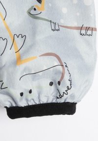 Ljust blått tyg med lekfulla djurillustrationer i grön, orange och brun. Manschetten har ett svart elastiskt band och ordet "äventyr".