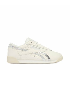 Low-profile white sneaker with metallic silver stripes and heel detail, lace-up closure, and perforations on side panel.