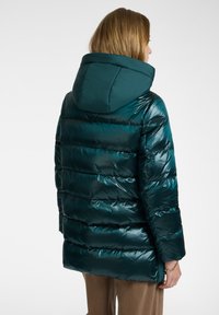 Tyrkysová péřová bunda s kapucí, s lesklým povrchem, vodorovným prošíváním a mírně oversize siluetou.