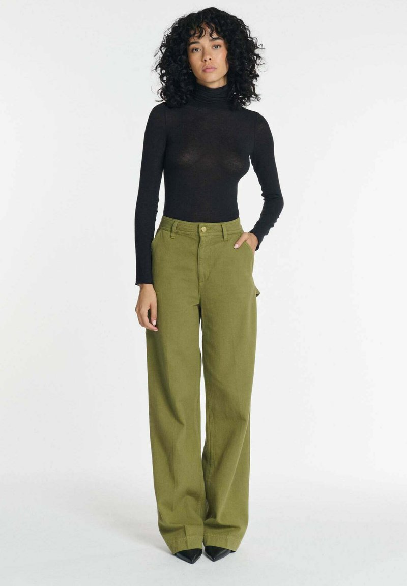 Zwarte coltrui en olijfgroene hoge taille wijde broek, met voorzakken en een elegante, gladde textuur.