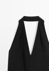 Robe noire à col licou avec un décolleté en V profond et un tissu fluide, présentant une texture lisse et un design minimaliste.