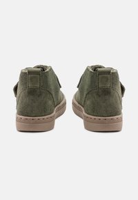 Stivaletti alla caviglia in suede verde con una texture morbida, punta rotonda e suola in gomma color tan, dotati di un anello sul retro per una facile calzata.