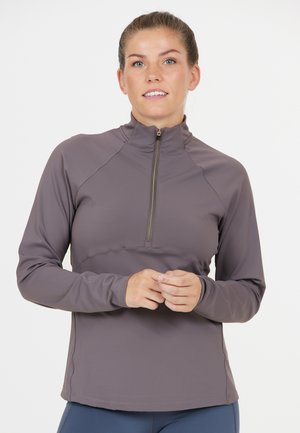 Langärmliges, helllila Sportoberteil mit Reißverschluss und hohem Kragen, flachen Nähten und weicher Textur. Verfügt über einen halben Reißverschluss für Belüftung.
