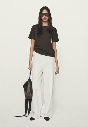 Bruine t-shirt, witte wijde broek, zwarte schoenen, gelaagde bruin crossbody tas en oversized donkere zonnebril. Minimalistisch ontwerp, neutrale kleuren.