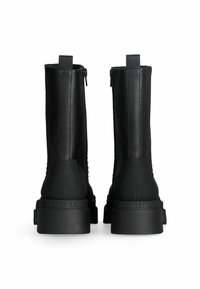 Stivaletti neri in pelle con suola in gomma spessa, dotati di chiusura con zip e pannello posteriore testurizzato. Il marchio è impresso sul tallone.