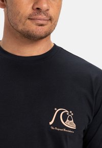 Černé bavlněné tričko s růžovým grafickým vzorem vlny a designem hory na levém hrudníku. Klasický crew neck a krátké rukávy.