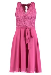 Rosa spetsklänning med v-ringning, ärmlös design och en flödande kjol. Har ett midjeband och en mjuk textur.