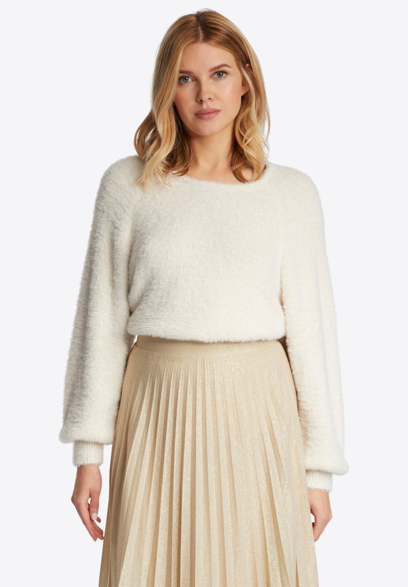 Witte, fluffy trui met lange mouwen, ronde hals, gedragen over een geplisseerde, metallic gouden rok. Zachte textuur en relaxte pasvorm.