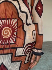 Robe en tissu à motifs et côtelée, présentant des tons terreux tels que le terracotta et la crème, ornée de motifs abstraits, d'accents en zigzag et de manches évasées.