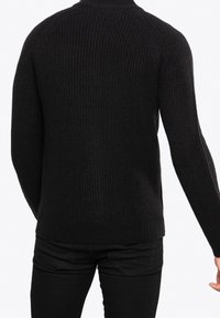 Czarny dzianinowy sweter o rypsowanej fakturze, z wysokim dekoltem i długimi rękawami. Tył ma bezszwowy design i dopasowany krój.