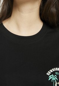 Černé bavlněné tričko s kulatým výstřihem, na levé horní straně s grafickým motivem bílé a tyrkysové palmy a textem.