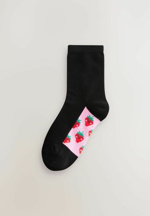 Chaussette en coton noire avec une bande rose affichant un motif de fraises en rouge et vert. Présente une texture côtelée et une forme standard.