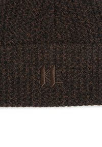 Brown knitted beanie with textured pattern, featuring a dark brown embroidered logo detail. The material appears soft and warm.