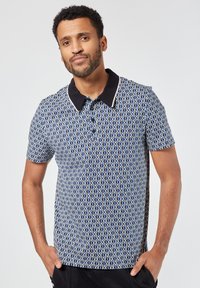 Lyhythihainen polo-paita tummansinisellä geometrisella kuviolla, Musta kaulus ja nappilista, valmistettu sileästä kankaasta.