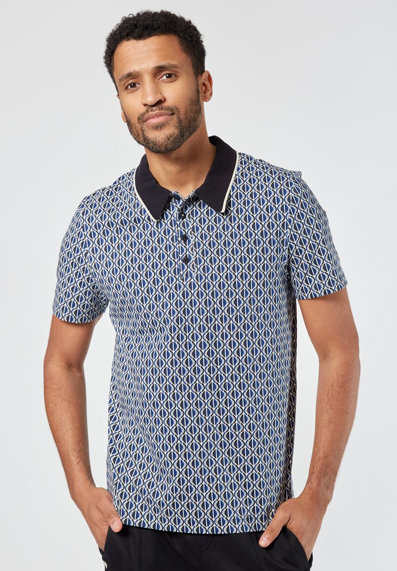 Lyhythihainen polo-paita tummansinisellä geometrisella kuviolla, Musta kaulus ja nappilista, valmistettu sileästä kankaasta.