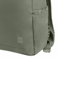 Zaino in tessuto verde con superficie testurizzata, tasca laterale e logo "GOT BAG" visibile sulla parte frontale. Forma rettangolare compatta.