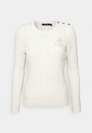 Hvid kabelstrikket sweater med lange ærmer, tre dekorative knapper på venstre skulder og broderet monogram på brystet.