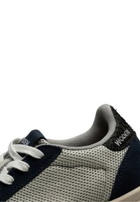 Sneaker da uomo in mesh grigio con dettagli in suede navy. Presenta lacci bianchi e un pannello posteriore nero texturizzato. Progettata per comfort e traspirabilità.