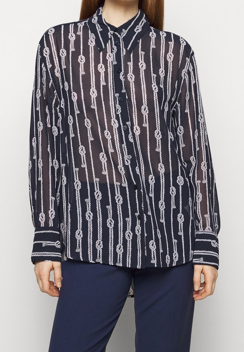 Blusa trasparente blu navy con motivo a nodo di corda bianca, chiusura frontale con bottoni, design con colletto e polsini a righe, caratterizzata da una vestibilità comoda e maniche lunghe.