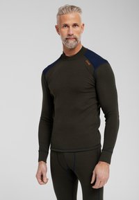 Oliven grøn termotop med lange ærmer, marineblå skulderdetaljer og kontrasterende syninger. Ribbet tekstur og tætsiddende design.