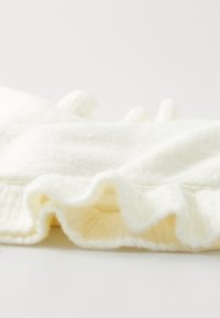 Valge, pehme kangas, millel on tekstureeritud pind ja rippuv äär. Tunnusjooned on sile ja fluffy välimus koos kerge läikega.