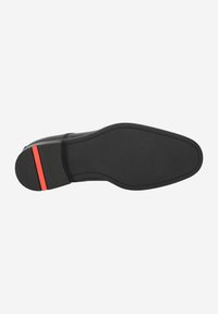 Suela de zapato negra con un acabado suave, que presenta un acento rojo en el talón y un patrón de agarre ligeramente texturizado en la parte inferior.