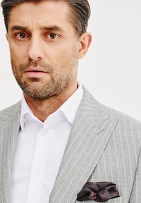 Szary garnitur w paski z białą koszulą, z ciemną poszetką o kwiatowym wzorze i teksturowanym wykończeniu.