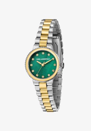 Rund ur med grøn urskive, guld- og sølvfarvet metalrem, diamantlignende markører og en tekstureret ring omkring urskiven. Brandnavn vist over urskiven.