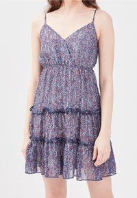 Robe sans manches, longueur genou, avec fines bretelles, volants superposés et un motif abstrait multicolore en bleu, violet et blanc.