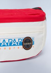Bolsa blanca y roja con un logotipo azul y un parche negro circular. La bolsa presenta una textura suave y una forma curvada con detalles en contraste.