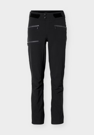 Pantalon d'extérieur noir avec deux poches avant zippées, une poche cuisse zippée, une fermeture double bouton et des jambes légèrement fuselées.