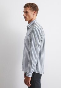 Striped button-up shirt in light blue and white. Features a classic collar, long sleeves, and a straight cut with side vents.