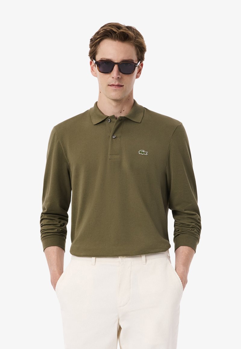 Olivgrünes Langarm-Polohemd mit klassischem Kragen, drei Knöpfen und einem kleinen gestickten Krokodil-Logo auf der linken Brust.