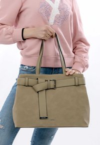 Borsa tote in pelle beige con finitura testurizzata, caratterizzata da una decorazione con cintura e dettaglio fibbia. Due manici robusti per il trasporto.