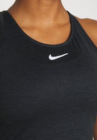 Canottiera sportiva nera realizzata in tessuto liscio, con scollo rotondo e logo Nike swoosh bianco sul petto.