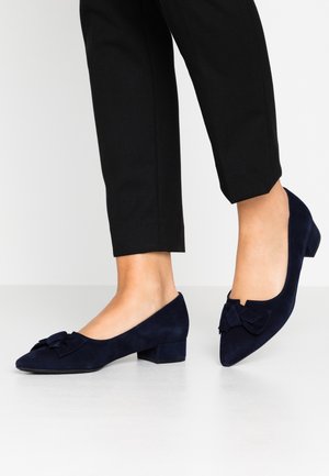 Granatowe zamszowe baleriny z małym obcasem, z ozdobną kokardką na czubku i gładką, matową fakturą.