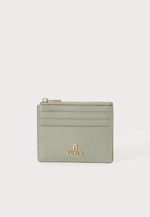 Porte-cartes en cuir vert clair texturé avec une fermeture éclair dorée et le logo Furla à l'avant, sur un fond clair uni.
