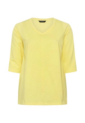 Chemise en coton jaune à col en V, manches trois-quarts, coupe ample et texture subtile, présentée sur un fond blanc.