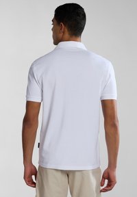 Polo bianco in cotone. Presenta un colletto, maniche corte e un orlo dritto. Nessun motivo o dettaglio visibile.