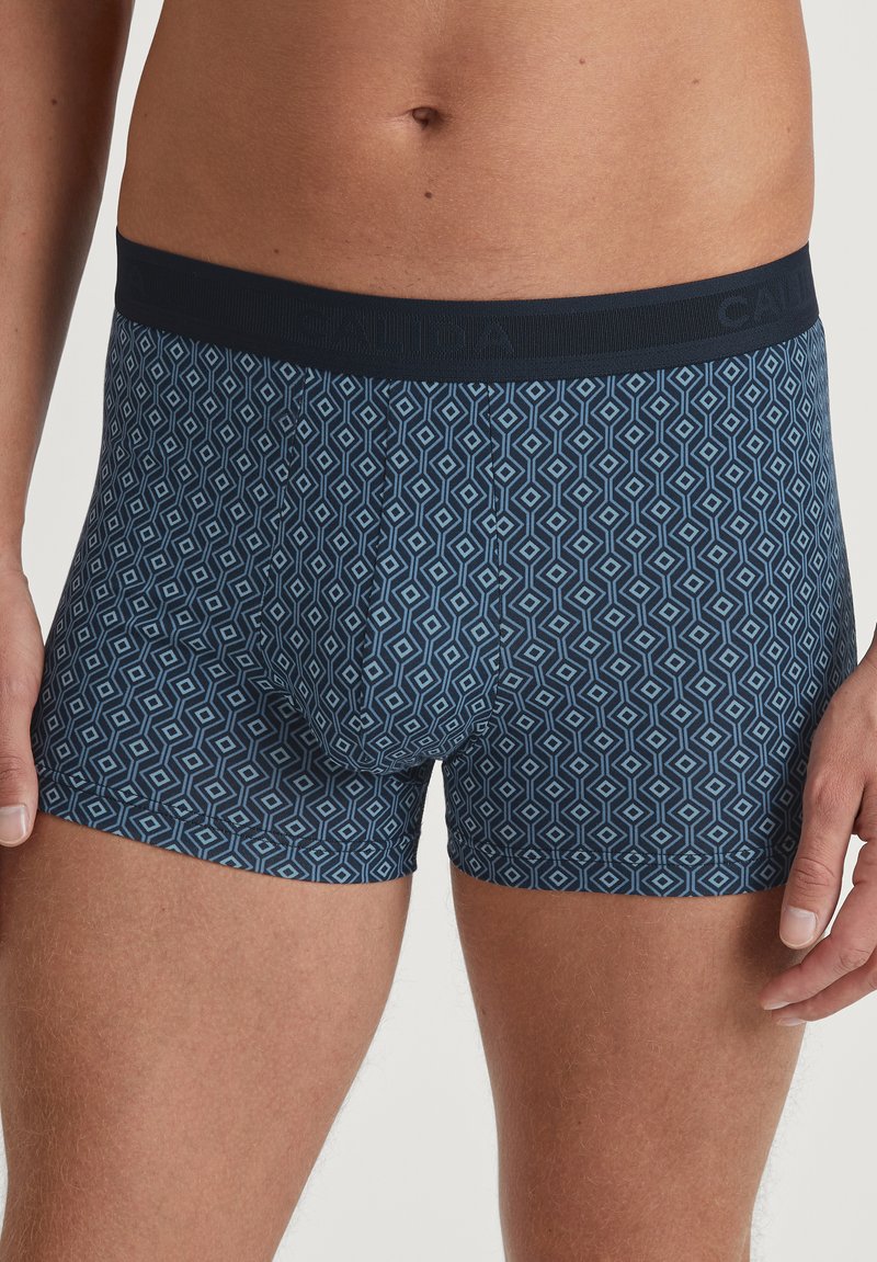 Marineblauwe boxershorts met een geometrisch diamanten patroon in blauw, met een donkere elastische tailleband met branding en een zachte stofstructuur.
