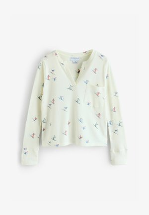 Vaaleankeltainen neulottu pusero pehmeällä tekstuurilla, jossa on V-aukko, pitkät hihat ja etutasku. Pusero on koristeltu värikkäillä hiihtokuvioilla.