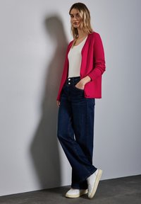 Fuchsiový kardigan, bílý dobře padnoucí top, tmavě modré široké džíny, bílé tenisky. Jednoduchý design s hladkou texturou a neutrálními akcenty.