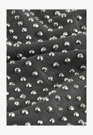 Textil mit einer dunkelgrauen Stoffoberfläche, die mit zahlreichen glänzenden silbernen Nieten verziert ist und ein strukturiertes, gemustertes Design erzeugt.