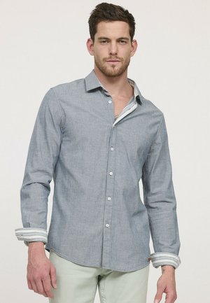 Chemise boutonnée bleu clair en tissu texturé, avec un col et des poignets rayés contrastants. Design ajusté, patte de boutonnage à l'avant.