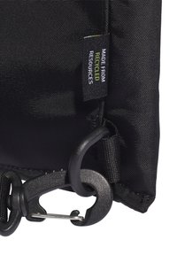 Černá textilní taška s texturovaným povrchem, vybavená kovovým klipem na uzávěr a štítkem s nápisem "Vyrobeno z recyklovaných zdrojů."