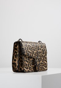 Torebka w panterkę z błyszczącym wykończeniem, o prostokątnym kształcie, z klapką i srebrnymi detalami na przodzie.