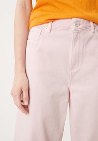 Jean en denim rose taille haute, design à cinq poches et quincaillerie métallique. Texture lisse avec des détails de couture visibles.